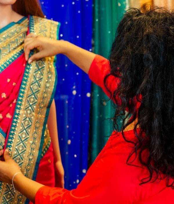 brunette indian woman choosing a new tradition saree in market.needlewoman designer drapery fabric dress on a mannequin.